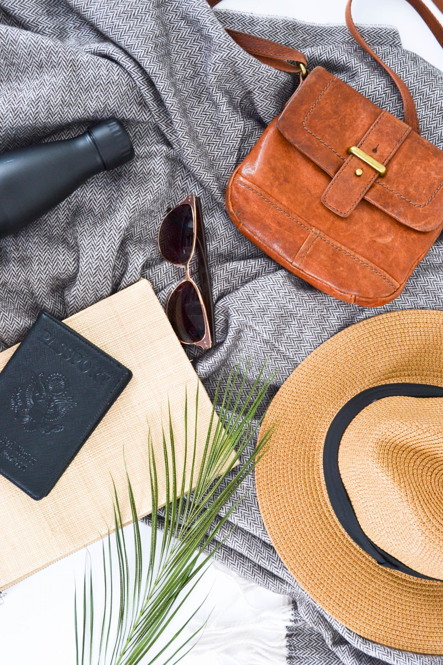 a flatlay with a bag, a hat, a waterbottle, sunglasses and two notebooks