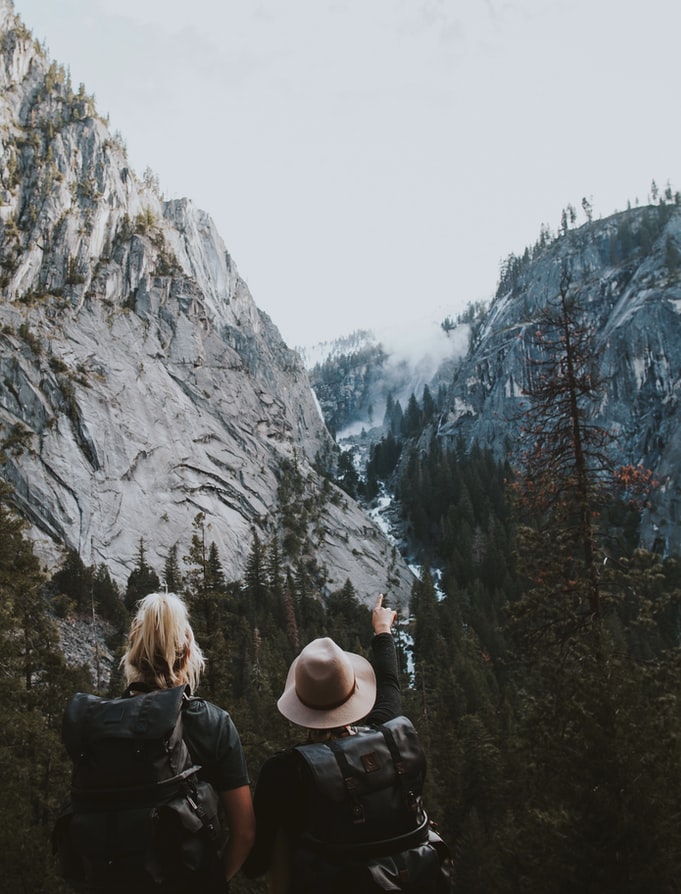 two people watching over the views in between two mountains with clouds