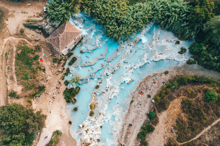 aerial view over trees, crystal blue water and a house