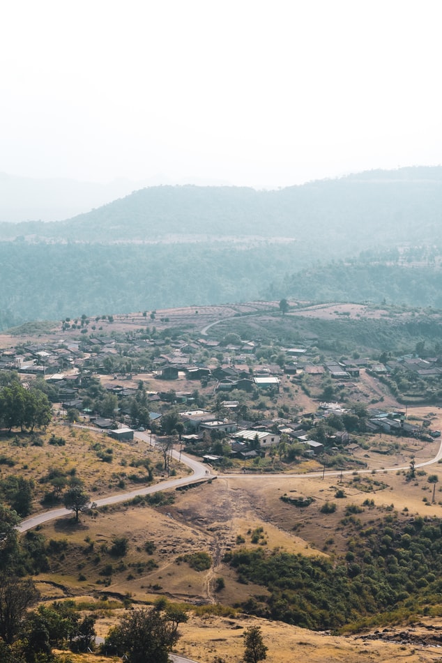 a view over a sunny city surrounded by nature and hills