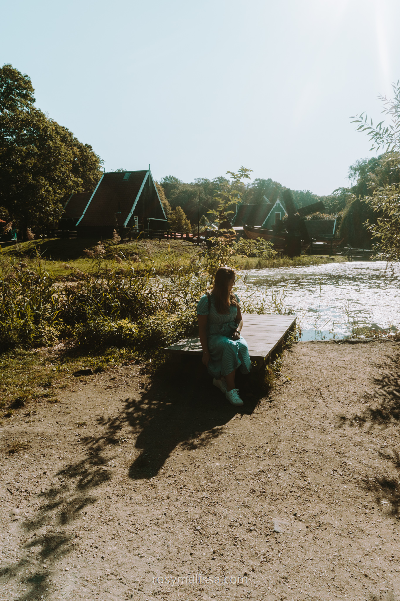 girl sitting on edge of the water, view on historic buildings in the netherlands